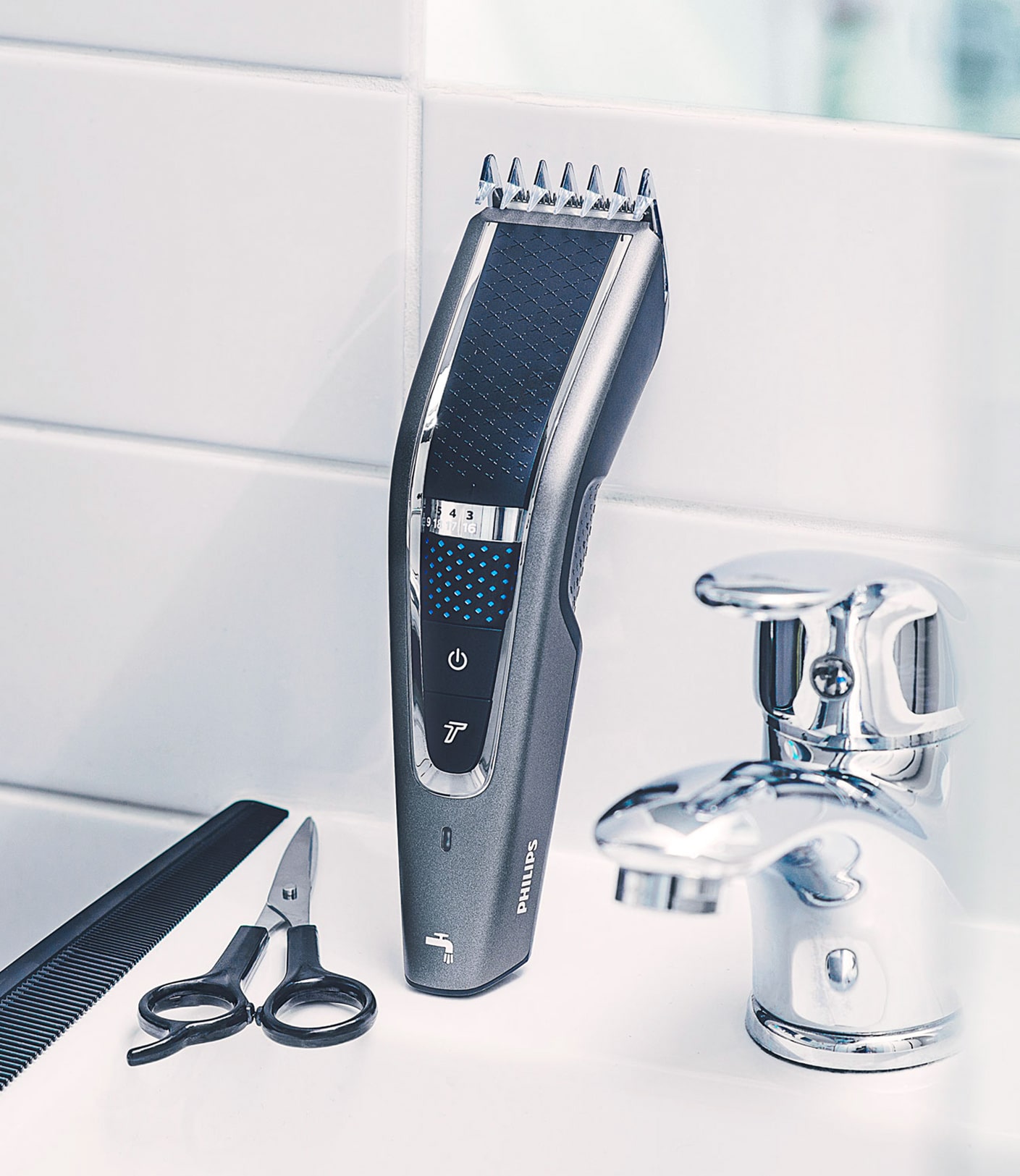 Mood photography of the Philips trimmer in bathroom, on the sink, with the accessories comb and scissor on its left