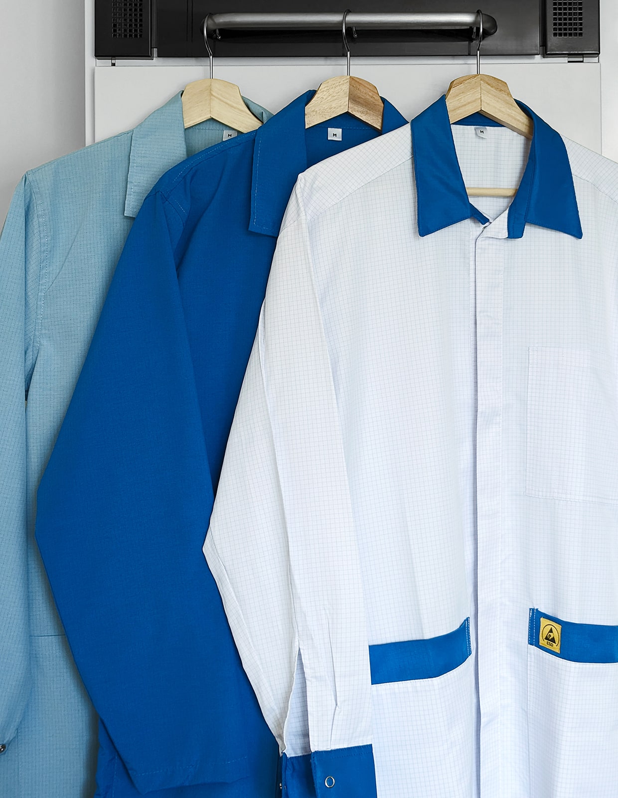 Behind the scenes photo of three hanging lab coats, ready for the photo shoot