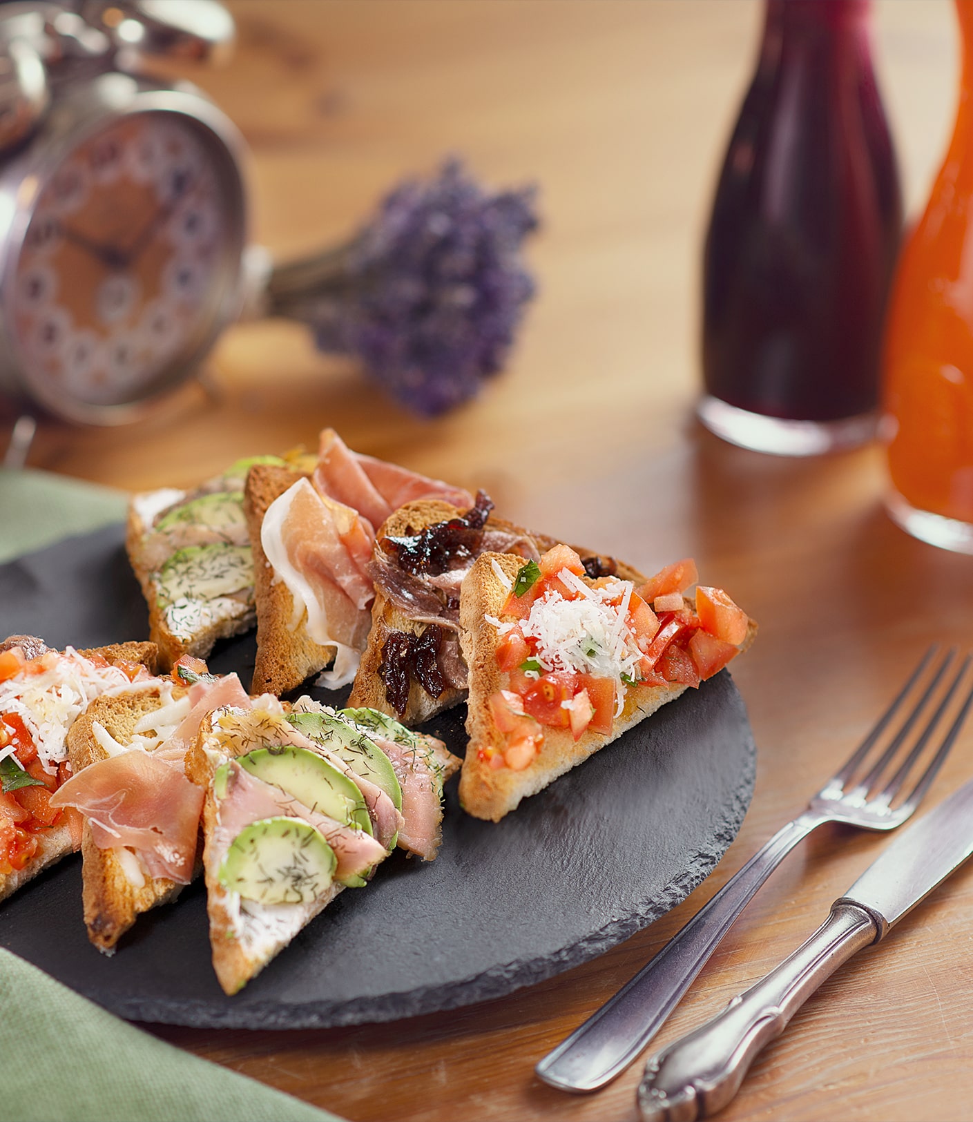 Mood photo of delicious slices of bread with avocado, salmon and tomatoes, with cozy wood background with a clock and a small lavender bouquet